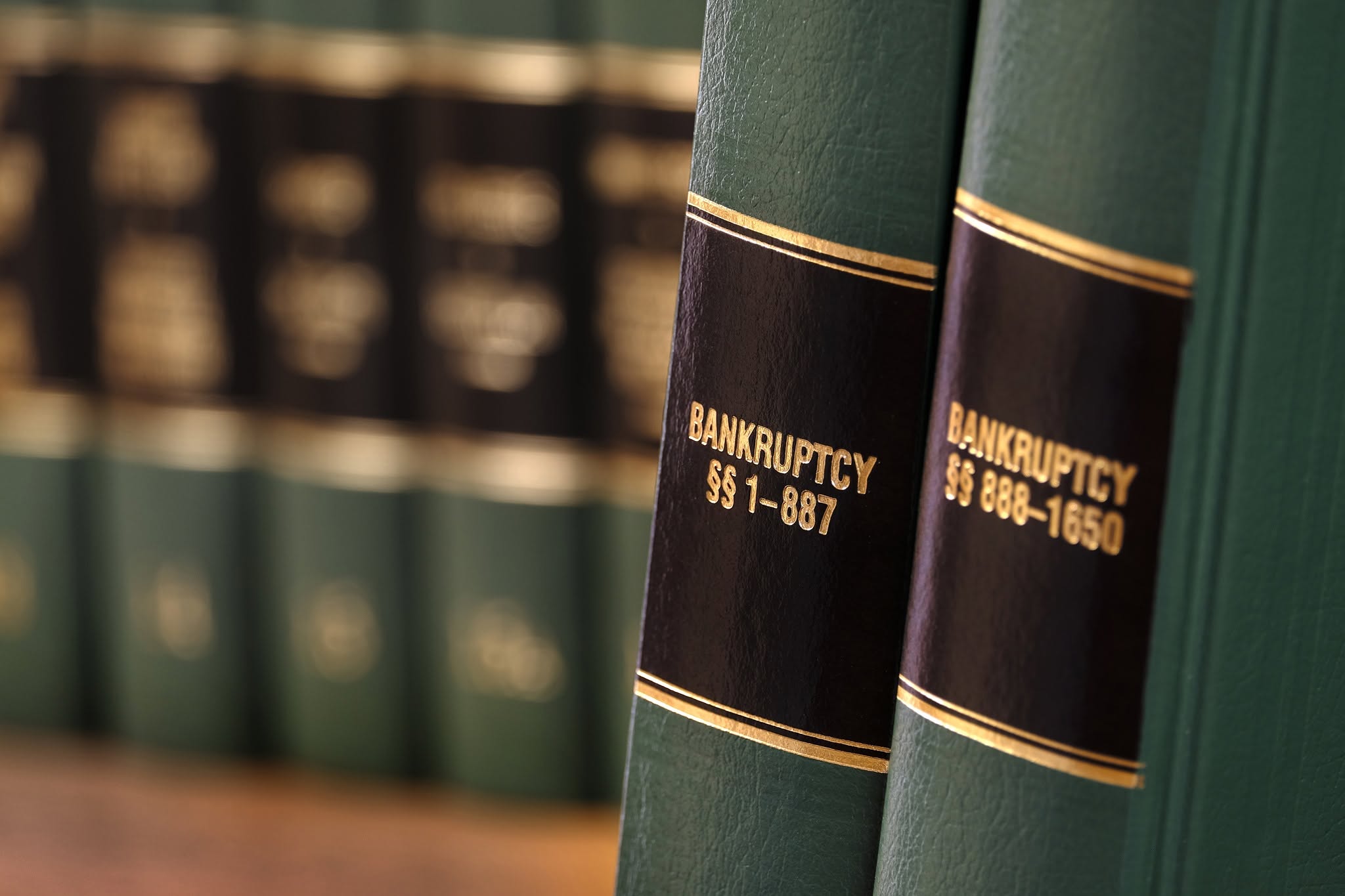 Two green leather bankruptcy law books with gold lettering on a shelf.